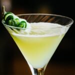 Close-up of a refreshing gin cocktail with cucumber garnish in a martini glass.